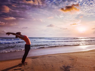 Sportif genç kadının yoga Sun salutation Surya Namaskar yapması yerleştirmek