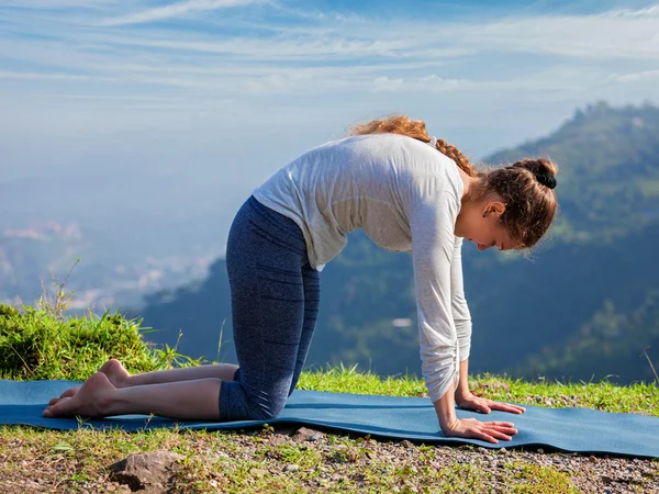 Mujer en forma deportiva practica yoga asana Marjariasana al aire libre — Foto de Stock