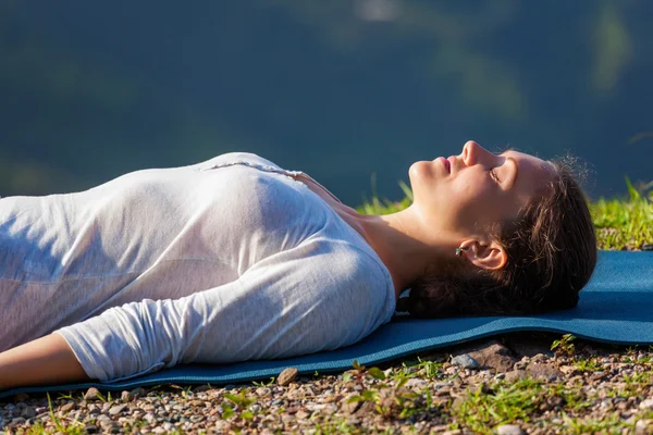 Vrouw ontspant in yoga asana Savasana buitenshuis — Stockfoto