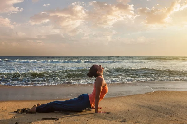 Frau praktiziert Yoga asana Urdhva Mukha Svanasana am Strand — Stockfoto