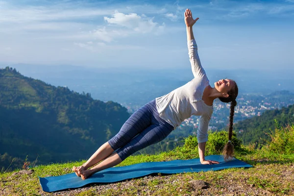 Nainen tekee jooga Asana Vasisthasana - puoli lankku aiheuttaa ulkona — kuvapankkivalokuva