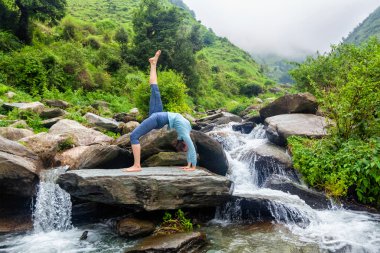 Şelalede yoga yapan kadın.