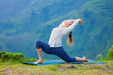 Sportif formda bir kadın dağlarda yoga yapıyor.