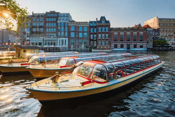 Łodzie turystyczne zacumowane w kanale Amsterdam molo o zachodzie słońca — Zdjęcie stockowe