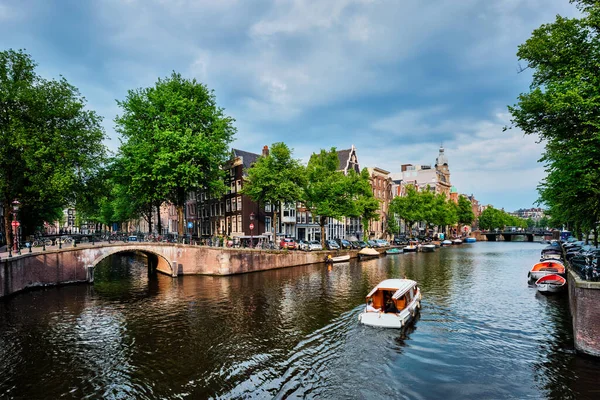 Вид Амстердама - канал с катером, мостом и старыми домами — стоковое фото