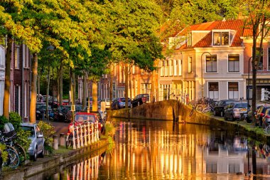 Gün batımında parkedilmiş eski evler ve arabalarla dolu delta kanalı.