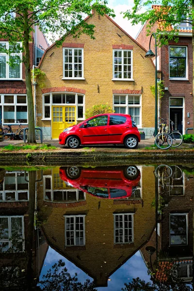 デルフトの街の運河堤防上の赤い車。オランダのデルフト — ストック写真