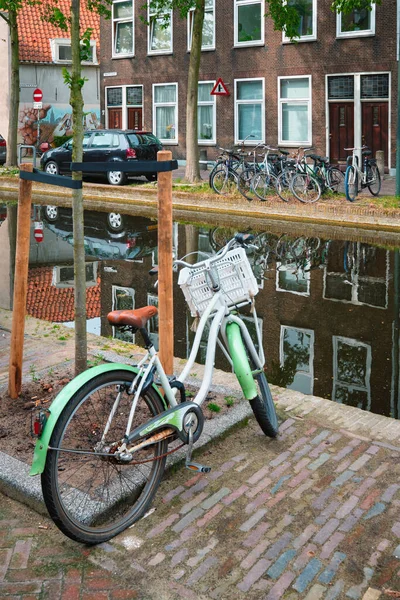 自転車は古い家とデルフトの通りの運河の近くに駐車しました。オランダのデルフト — ストック写真