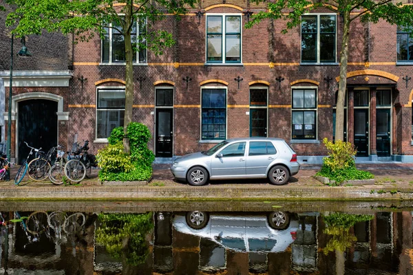 デルフトの街の運河堤防上の車。オランダのデルフト — ストック写真