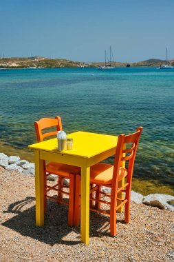 Milos Adası 'ndaki Adamantas kasabasında, Ege Denizi' nin arka planında tekneleri olan kafe masası.