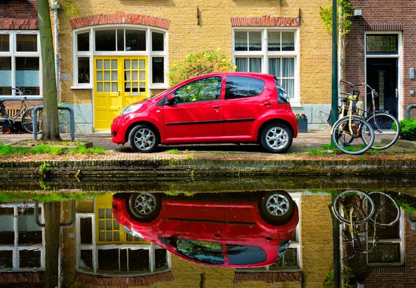 デルフトの街の運河堤防上の赤い車。オランダのデルフト — ストック写真