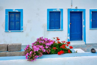 Yunanistan 'ın Santorini adasındaki Oia köyünü mavi kapısı ve pencereli Yunan beyaz evi kör etti