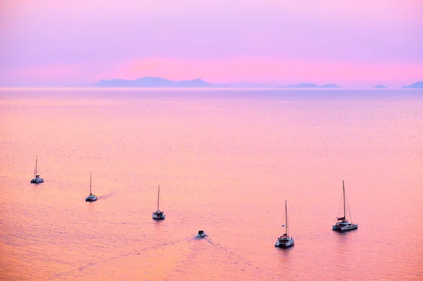 Barco de iates turísticos no mar Egeu perto da ilha de Santorini, com turistas assistindo ao pôr do sol miradouro. Santorini, Grécia — Fotografia de Stock