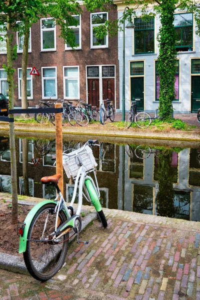 自転車は古い家とデルフトの通りの運河の近くに駐車しました。オランダのデルフト — ストック写真