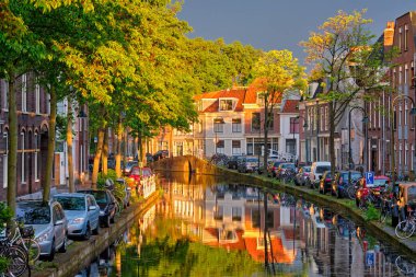 Gün batımında parkedilmiş eski evler ve arabalarla dolu delta kanalı.