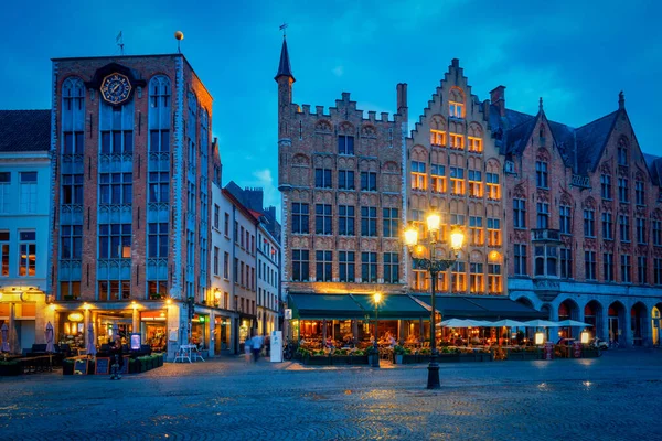 Bruges Grote markt tér kávézóval és éttermekkel az esti szürkületben — Stock Fotó