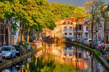 Gün batımında parkedilmiş eski evler ve arabalarla dolu delta kanalı.