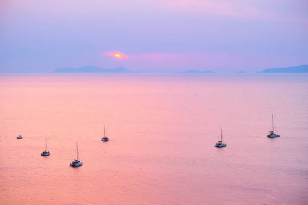 Туристические яхты в Эгейском море недалеко от острова Санторини с туристами, смотрящими на закат. Санторини, Греция — стоковое фото