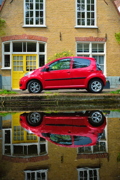 Carro vermelho no aterro do canal na rua de Delft. Delft, Países Baixos — Fotografia de Stock