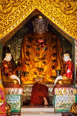 Buddhist monk praying in Shwedagon pagoda clipart