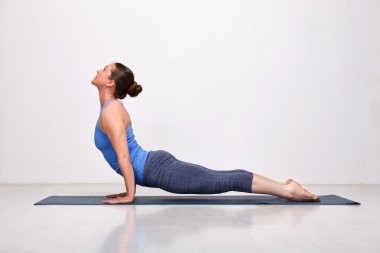 Sporty fit yogini woman practices yoga asana Urdhva mukha svanas clipart
