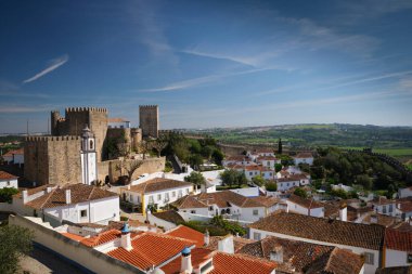 Obidos Ortaçağ Şatosu, Portekiz 'in zengin tarihini ve berrak mavi gökyüzü altındaki büyüleyici manzarasını gözler önüne seren eski evlerin üzerinde dimdik duruyor..