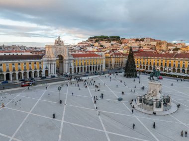 Praca do Comercio 'da güzel bir kış günbatımı. Arco da Rua Augusta ve insanlarla çevrili süslü bir Noel ağacı. Lizbon, Portekiz