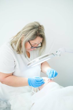 Bir estetisyen kozmetik uzmanı metal çıkarıcı kullanarak gözenekleri temizler ve daha açık bir cilt için lekeleri temizler..