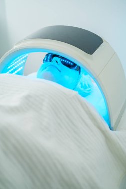 Mavi ışık terapisi istemcisi, sivilce yapan bakterileri hedef almak için LED ışık terapisiyle yüz temizleme programından geçiyor..