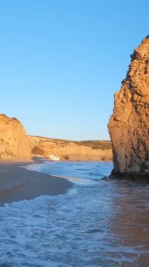 Fyriplaka sahilindeki kayaların yanında yürümek ve gün batımında Ege Denizi 'nin dalgaları, Milos Adası, Kiklad, Yunanistan. Sabit kamera görüntüsü