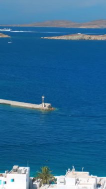 Meşhur yel değirmenleriyle Mykonos kasabası manzarası ve yaz günü tekneleri ve yolcu gemisi olan liman manzarası. Mykonos, Cyclades adaları, Yunanistan. Kamera tavasıyla