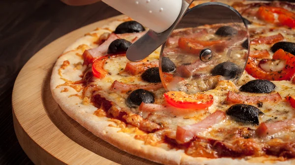 Pizzaschneiderrad schneidet Schinken-Pizza — Stockfoto