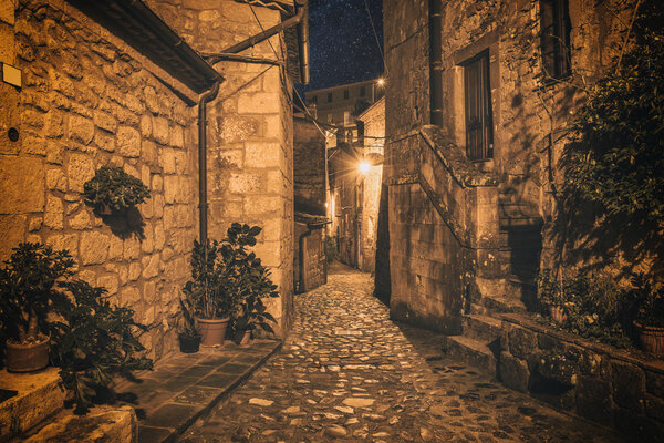 Street of ancient medieval tuff city Sorano at night - travel european background