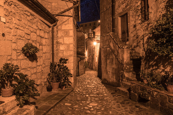 Street of ancient medieval tuff city Sorano at night - travel european background