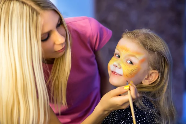 Žena, malování obličej holčičky — Stock fotografie