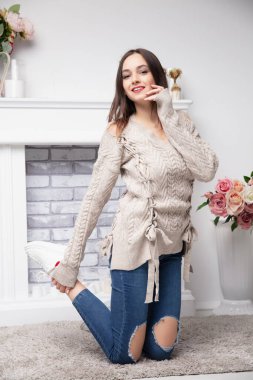 Pantolon ve şöminenin yanında poz veren bir süveter giymiş güzel bir esmer.