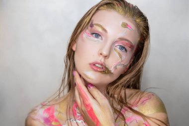 Yüzünde yaratıcı bir makyajı olan genç bir kadının portresi.