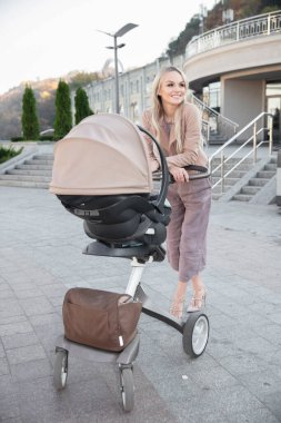 Güzel bir anne ve dışarıda yürüyen bir bebek arabası.