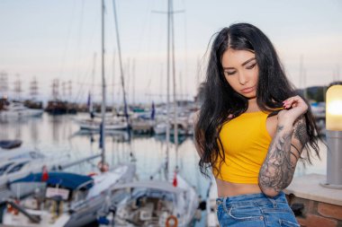 Deniz ve yatın arka planında poz veren çekici bir esmerin portresi