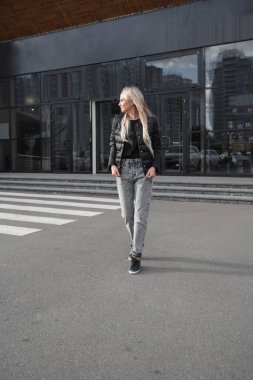 Siyah ceket ve kot giyen hoş bir kadın.