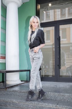 Binanın yakınında siyah tişört ve kot pantolon giyen hoş bir bayan.