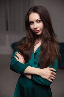 Stüdyoda poz veren yeşil ipekli bir esmer kızın portresi.