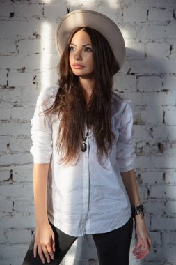 Stüdyoda duvarın yanında poz veren güzel bir kadın.