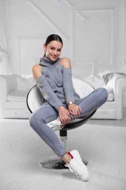 Gri bir kazak ve kotla stüdyoda poz veren güzel bir esmer.