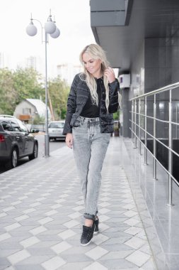 Korkulukların ve binanın yanında duran genç, seksi sarışın.