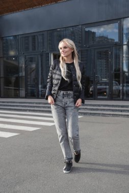 Siyah ceket ve kot giyen hoş bir kadın.