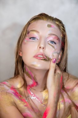 Yüzünde yaratıcı bir makyajı olan çekici bir genç kadının portresi.