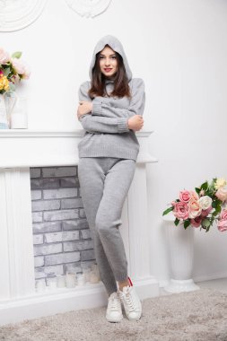 Gri takım elbiseli, şöminenin yanında poz veren çekici bir esmer.