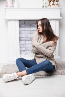 Pantolon ve şöminenin yanında poz veren güzel bir esmer.