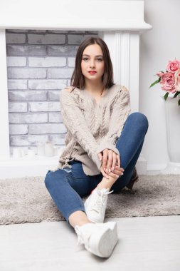 Pantolon giyip şöminenin yanında poz veren hoş bir esmer kız.